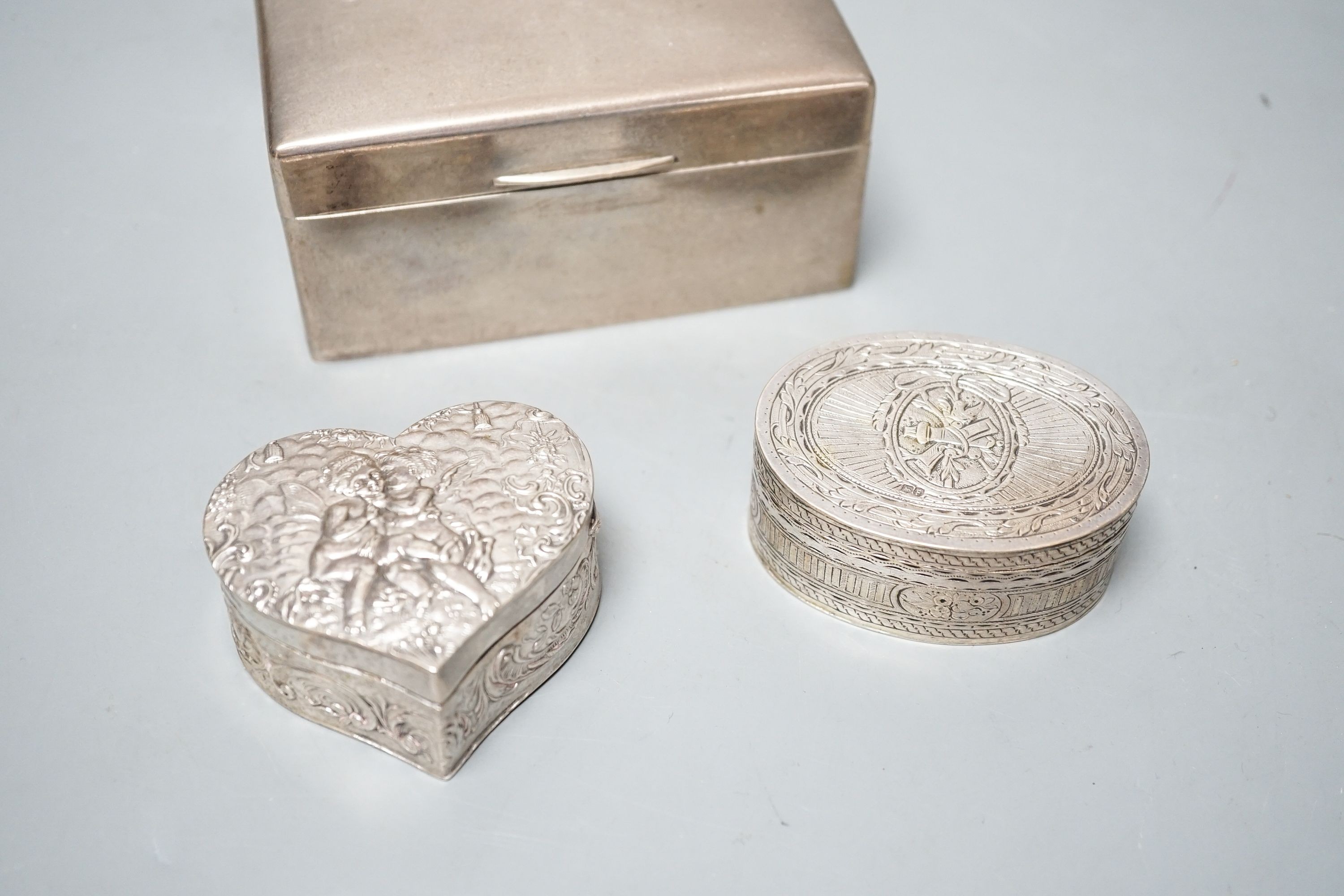 A continental oval white metal snuff box, engraved with hunting scenes, 72mm, a silver oval snuff box with Sheffield, import marks, a silver heart shaped box and a silver cigarette box.